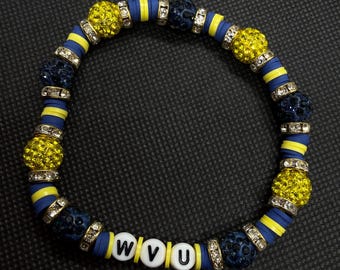 Può includere: Un braccialetto di perline con dischi piatti blu e gialli, sfere testurizzate blu scuro, sfere giallo brillante incastonate di strass e distanziatori color argento. Sono incluse tre perline bianche sferiche con le lettere nere W, V e U.