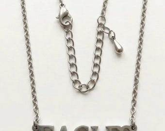 Può includere: Una collana in metallo color argento con un ciondolo che riporta la parola EAGLES in lettere maiuscole. La collana presenta una sottile catena a maglie, una chiusura a moschettone e una catenella di estensione regolabile con un piccolo ciondolo a goccia.