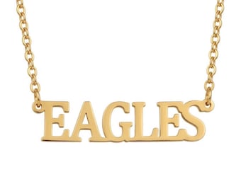 Può includere: Una collana color oro con un ciondolo a targhetta orizzontale che riporta la parola EAGLES in un carattere serif in grassetto e maiuscolo. Il ciondolo è fissato a una sottile catena a maglie su entrambi i lati, creando un gioiello raffinato.