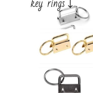 May include: Three key rings with a swivel clasp and a metal ring. The key rings are silver, gold, and black.