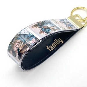 May include: A black leather keychain with a clear plastic strip featuring multiple photos of a family. The keychain has a gold metal ring and the word "family" is embossed in gold on the leather.