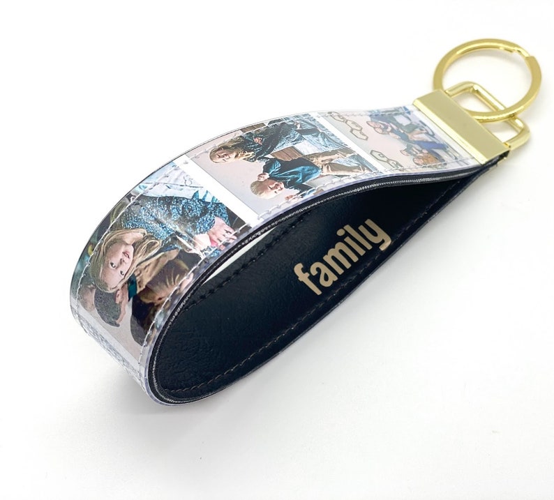 May include: A black leather keychain with a clear plastic strip featuring multiple photos of a family. The keychain has a gold metal ring and the word "family" is embossed in gold on the leather.
