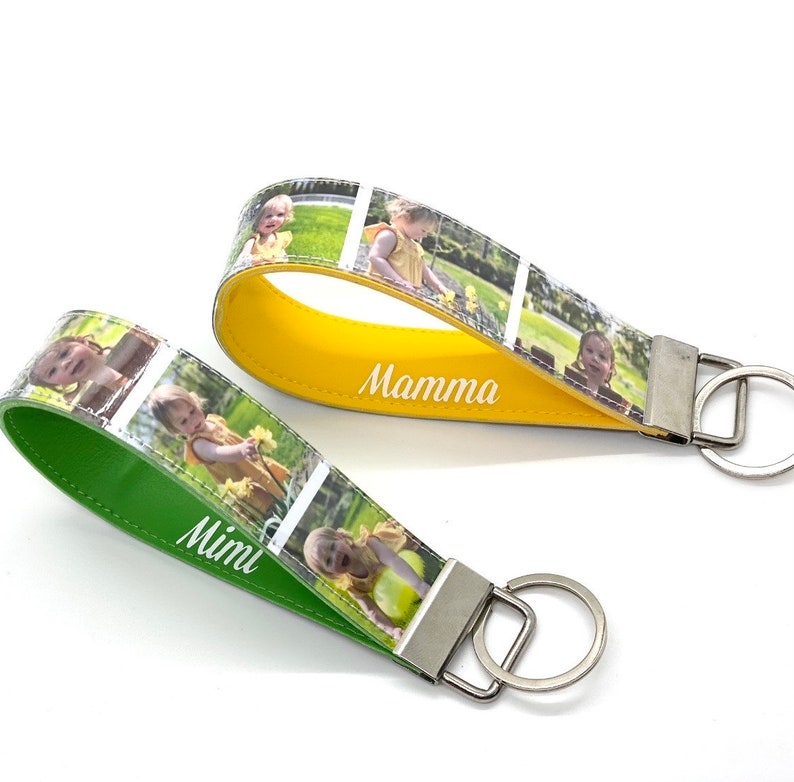 May include: Two personalised photo keychains with green and yellow leather straps. The keychain on the left has the word "Mimi" written on the strap and the keychain on the right has the word "Mamma" written on the strap.