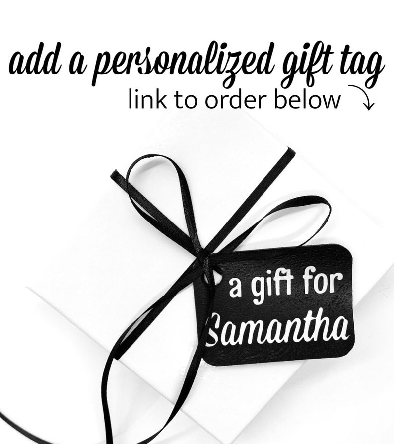 May include: A white gift box with a black ribbon and a black gift tag that says "a gift for Samantha".