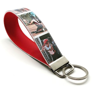 May include: Red leather keychain with a photo strip design featuring a girl playing baseball. The keychain has a silver metal key ring.