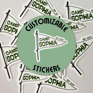 May include: A collection of white flag-shaped stickers with the text "CAMP SOPHIA" in a dark green font. The stickers also include the text "EST. 2027". A green circle in the center reads "CUSTOMIZABLE STICKERS".