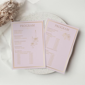 May include: Two pink event programmes with gold borders and text. The programmes feature event details, including a slideshow and candle lighting. Gold candle illustrations and floral accents add elegance. The programmes are on a white surface.