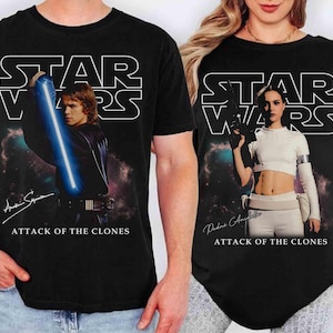 May include: Black t-shirts featuring Star Wars graphics. One shirt displays Anakin Skywalker with a blue lightsaber, the other shows Padmé Amidala holding a blaster. Both shirts have the Star Wars logo and "Attack of the Clones" text.