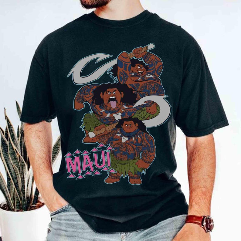 May include: Black t-shirt featuring a graphic of the character Maui from the animated film Moana. The design includes three illustrations of Maui with tattoos, a hook, and the word "MAUI" in pink letters.
