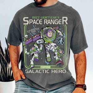 Puede incluir: Camiseta gris oscuro con un gr&aacute;fico de Space Ranger de Buzz Lightyear. El dise&ntilde;o incluye a Buzz Lightyear con un traje espacial verde y blanco, con el texto "Space Ranger de Buzz Lightyear" y "Galactic Hero". Establecido en 1998.