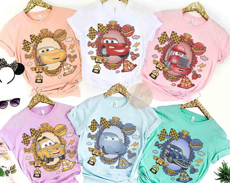 Puede incluir: Colecci&oacute;n de seis camisetas de manga corta en varios colores pastel, cada una con un dise&ntilde;o de coche de dibujos animados dentro de un marco ornamentado. Los dise&ntilde;os incluyen a Rayo McQueen y otros personajes de la franquicia Cars. Las camisetas se muestran en perchas doradas.
