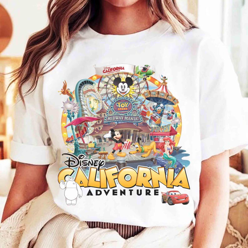 May include: White t-shirt featuring a colorful graphic of Disney California Adventure. The design includes Mickey Mouse, a Ferris wheel, and various Disney characters. The words "Disney California Adventure" are prominently displayed.