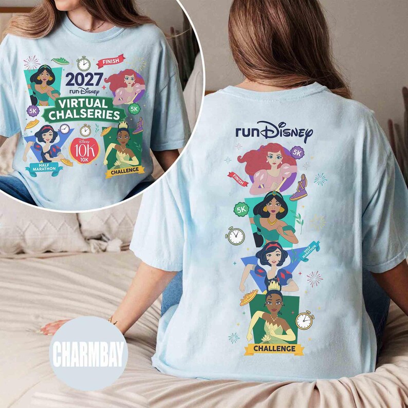 May include: A light blue t-shirt featuring Disney princess graphics. The front displays 2027 runDisney Virtual Chalseries text with characters Ariel, Jasmine, Snow White, and Tiana. The back shows the runDisney logo and the same characters stacked vertically.