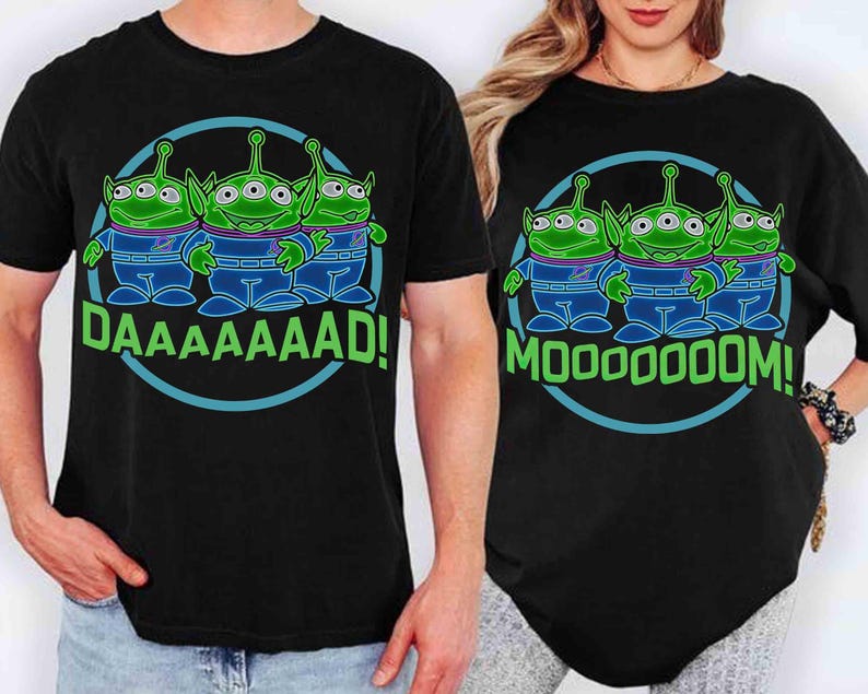 May include: Black t-shirts featuring a cartoon graphic of three green aliens with three eyes, wearing blue and purple outfits, inside a blue circle. One shirt says "DAAAAAAAD!" and the other says "MOOOOOOOM!"