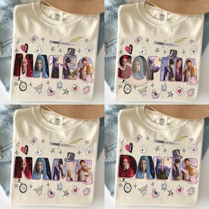 May include: A cream-colored t-shirt featuring a custom name graphic where each letter contains a different character or scene. The design includes scattered illustrations of a sword, lightning bolt, stars, hearts, flowers, and a teapot.