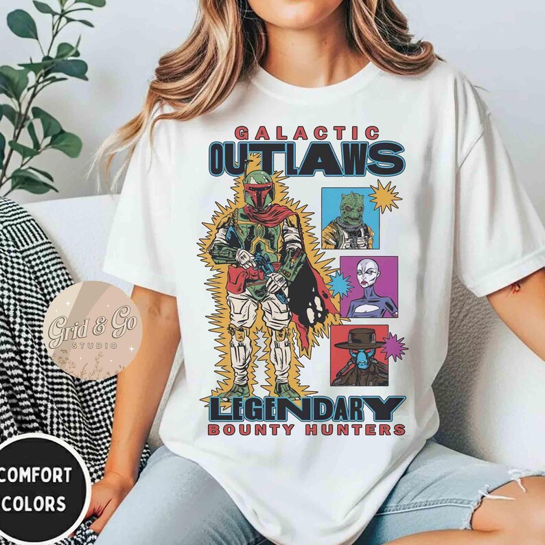 May include: White t-shirt with a colourful graphic featuring the text "GALACTIC OUTLAWS LEGENDARY BOUNTY HUNTERS." The design includes illustrations of several characters in a comic book style.