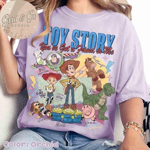 May include: Orchid-colored t-shirt featuring a graphic of Toy Story characters, including Woody, Buzz Lightyear, and Rex. The shirt has the text "TOY STORY" and "You've Got a Friend in Me". The shirt is a comfortable, casual wear item.