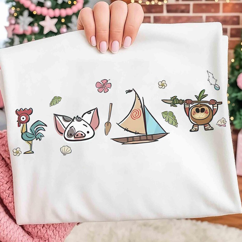 Puede incluir: Una camiseta blanca con un estampado gr&aacute;fico colorido de un gallo de dibujos animados, un lech&oacute;n, un remo de madera, un velero con una vela en espiral y un peque&ntilde;o personaje de coco sosteniendo una lanza, rodeado de flores, hojas y conchas.