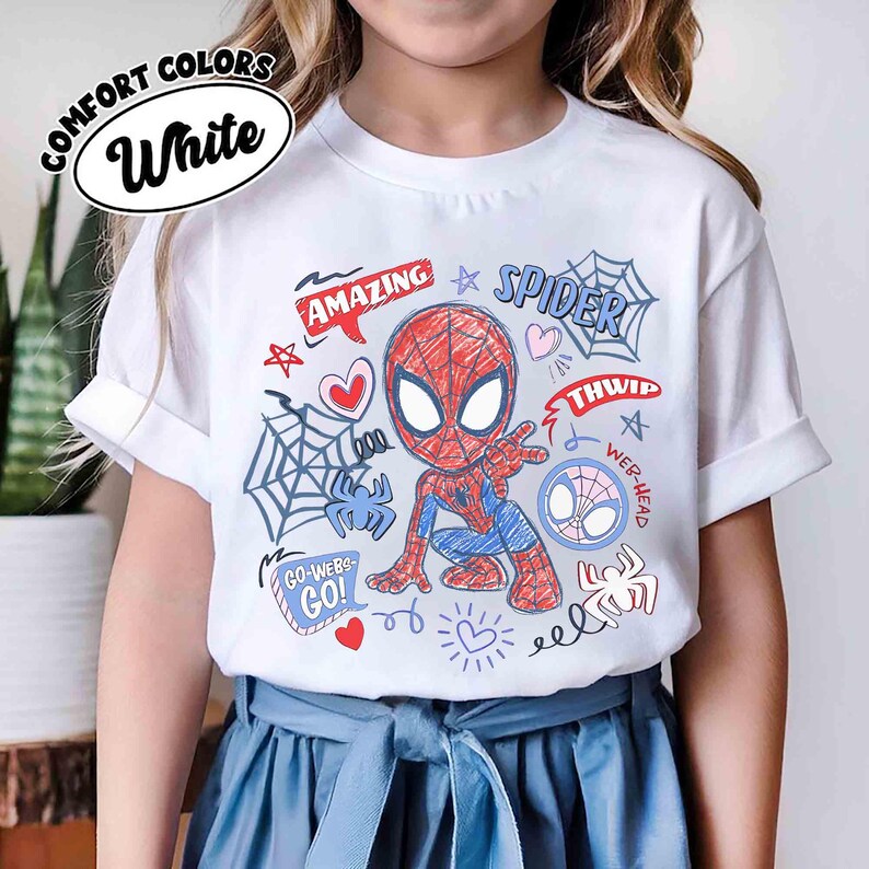 May include: White t-shirt featuring a colorful Spider-Man graphic. The design includes the words "AMAZING" and "SPIDER", along with spider webs, hearts, and the phrases "GO-WEB-GO!" and "WEB-HEAD". The shirt is made of Comfort Colors material.