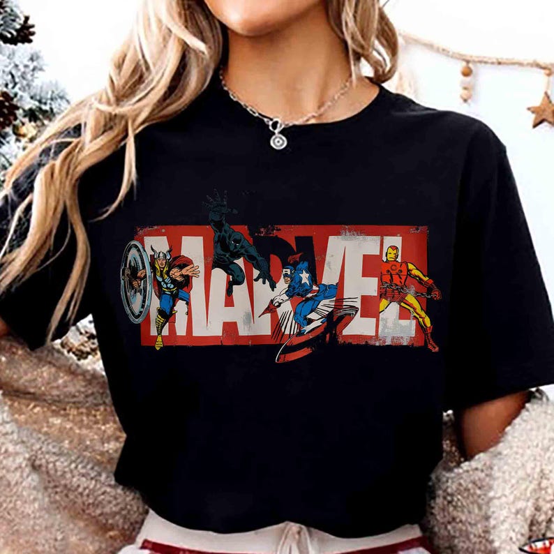 Puede incluir: Camiseta negra con el logo de Marvel en rojo y blanco, con ilustraciones de Thor, Black Panther, Capit&aacute;n Am&eacute;rica e Iron Man. El dise&ntilde;o es de estilo c&oacute;mic vintage.