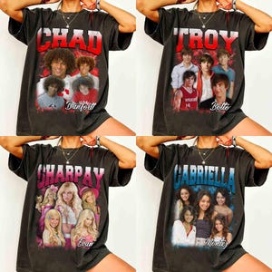 Könnte beinhalten: Vier dunkelgraue T-Shirts mit unterschiedlichen Designs. Eines zeigt den Namen "CHAD" mit Bildern von Schauspielern. Ein anderes zeigt "TROY" mit Bildern von Schauspielern. Das dritte zeigt "SHARPAY" mit Bildern von Schauspielerinnen. Das letzte zeigt "GABRIELLA" mit Bildern von Schauspielerinnen.