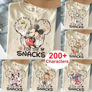 May include: Cream-colored t-shirts with various cartoon character designs. One shirt features Mickey Mouse with the text "I'm just here for the snacks." Other shirts showcase Buzz Lightyear, Minnie Mouse, a fox, Woody, and Spider-Man.