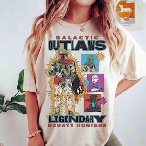 May include: Cream-coloured t-shirt with a graphic of a bounty hunter and the text "GALACTIC OUTLAWS LEGENDARY BOUNTY HUNTERS." The design includes images of various characters in a retro comic book style.