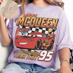 Pu&ograve; includere: T-shirt color orchidea con grafica di Saetta McQueen del film Cars. Il design include il testo "Lightning McQueen", "Cars", "Think Fast" e il numero "95". La maglietta ha una vestibilit&agrave; ampia.
