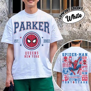 K&ouml;nnte beinhalten: Wei&szlig;es T-Shirt mit einem Spider-Man-Design. Die Vorderseite zeigt "PARKER" in Blau und Rot, mit "QUEENS NEW YORK" unter einer Spider-Man-Grafik. Die R&uuml;ckseite zeigt Spider-Man und zugeh&ouml;rigen Text.