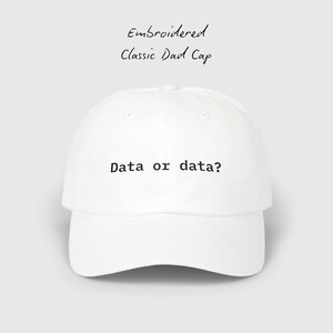 May include: White embroidered classic dad cap with the text "Data or data?" in black. The cap has a curved brim and a structured crown. The words "Embroidered Classic Dad Cap" are written above the cap.
