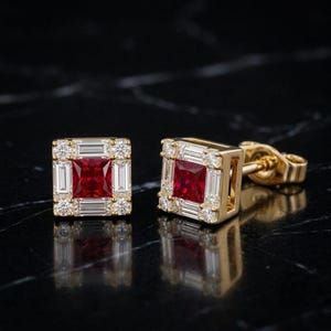 Könnte beinhalten: Ein Paar quadratische Ohrstecker aus Gelbgold, jeweils mit einem zentralen, im Prinzessschliff geschliffenen roten Rubin, umgeben von einem Kranz aus weißen Diamanten im Baguette- und Brillantschliff, mit sicheren Steckverschlüssen.