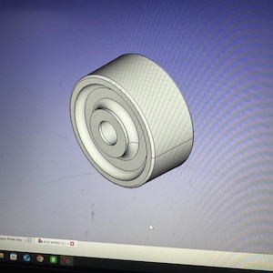 May include: A 3D rendering of a white wheel with a central hole and concentric circular grooves. The wheel is displayed against a blue and gray background, likely a computer screen.