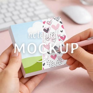 May include: A notepad mockup with a sky and cloud design on the left and a pattern of hearts on the right. The words "notepad MOCKUP" are overlaid on the notepad. A pink pen is held over the notepad.