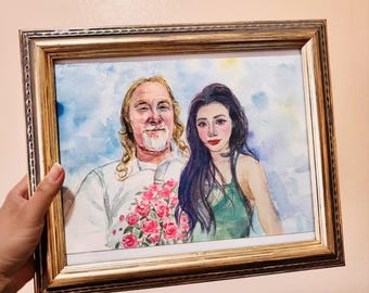 May include: Watercolor portrait of a couple in a gold-colored frame. The man has long blonde hair and a white shirt, holding a bouquet of pink roses. The woman has long black hair and a green top. The background is a watercolor wash of blue and white.