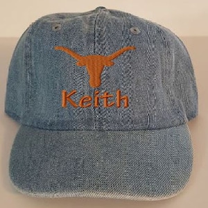 May include: A blue denim baseball cap with an orange embroidered Texas Longhorns logo and the name "Keith" stitched below it.