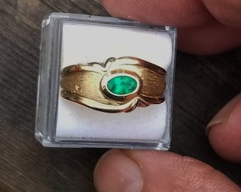 May include: A gold ring with a green oval gemstone set in the center. The ring is in a small white box.