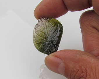 May include: A carved green and brown gemstone pendant with a leaf design.