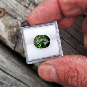 Peut inclure: Une pierre précieuse ovale verte dans une petite boîte en plastique transparente.