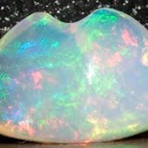 May include: A white opal cabochon with green, blue, and pink flashes of color. The opal is a freeform shape and has a smooth, polished surface.