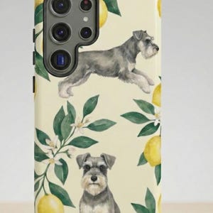 May include: A phone case featuring a watercolor design with two Schnauzer dogs, lemons, and lemon blossoms on a cream background. The case has a camera cutout and a black border.