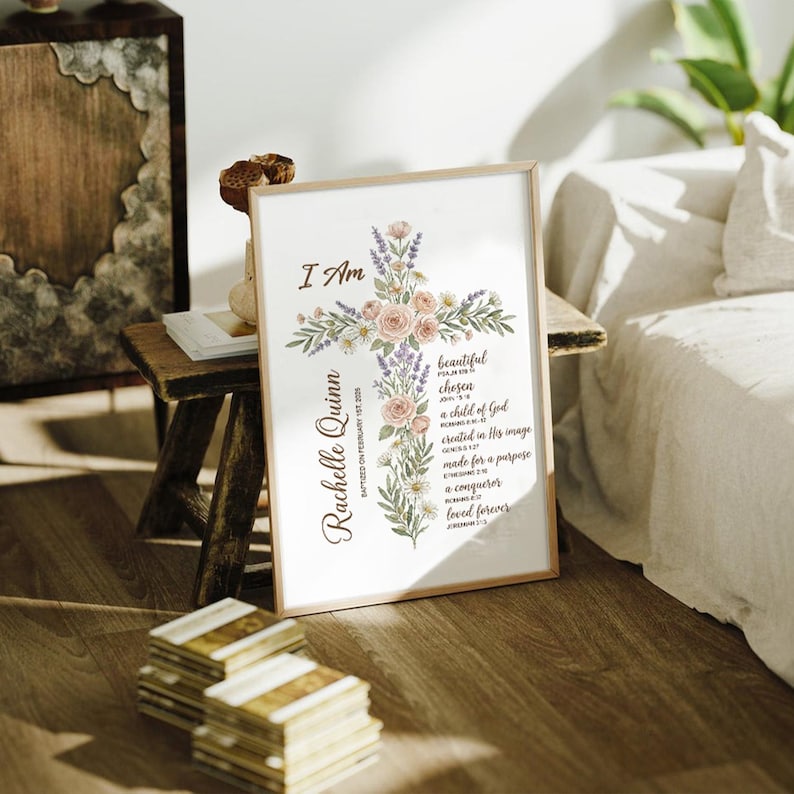 Puede incluir: Un estampado enmarcado con un dise&ntilde;o de cruz floral con las palabras "I Am" en la parte superior. La cruz est&aacute; adornada con rosas rosas, lavanda y vegetaci&oacute;n. El nombre "Rachelle Quinn" est&aacute; impreso verticalmente a la izquierda, con texto adicional debajo.