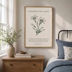 May include: A vertical wall art print featuring a black line drawing of lilies on a cream background. The text reads: CONSIDER THE LILIES of the field, how they grow: they neither toil nor spin; and yet I say to you that even Solomon in all his glory was not arrayed like one of these. MATTHEW 6:28.