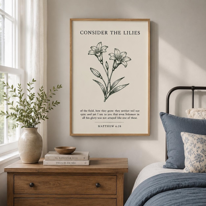 May include: A vertical wall art print featuring a black line drawing of lilies on a cream background. The text reads: CONSIDER THE LILIES of the field, how they grow: they neither toil nor spin; and yet I say to you that even Solomon in all his glory was not arrayed like one of these. MATTHEW 6:28.
