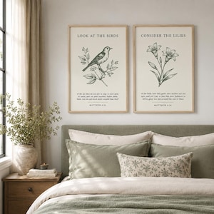 May include: Two rectangular wall art prints in light wood frames featuring cream backgrounds. The left print shows a bird on a branch with the text "LOOK AT THE BIRDS" and "MATTHEW 6:26". The right print shows lilies with "CONSIDER THE LILIES" and "MATTHEW 6:28".