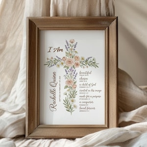 Puede incluir: Una impresi&oacute;n enmarcada con un dise&ntilde;o de cruz floral. La cruz est&aacute; adornada con rosas de color rosa claro, lavanda y margaritas blancas. El texto incluye "I Am", el nombre "Rachelle Quinn" y frases inspiradoras como "beautiful" y "chosen".