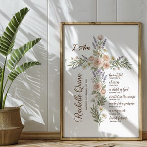 Puede incluir: Una impresi&oacute;n enmarcada con un dise&ntilde;o de cruz floral con las palabras "I Am" en la parte superior. La cruz est&aacute; adornada con rosas, margaritas y lavanda. Se incluye el nombre "Rachelle Quinn" y la fecha del bautizo. Tambi&eacute;n hay texto inspirador.