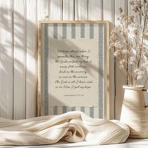 May include: A framed print with a beige and gray striped background and a torn paper overlay. The text reads "Yet hope returns when I remember this one thing: the Lord's unfailing love & mercy still continue..." Lamentations 3:21-24.