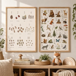 May include: Two framed educational wall art prints featuring a numbered counting chart from one to ten with nature illustrations and an alphabet chart from A to Z with woodland animals and plants, displayed on a wooden shelf with a plush fox toy.