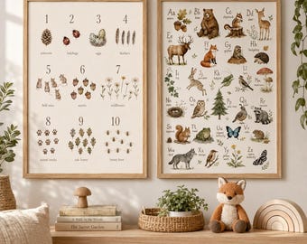 May include: Two framed educational wall art prints featuring a numbered counting chart from one to ten with nature illustrations and an alphabet chart from A to Z with woodland animals and plants, displayed on a wooden shelf with a plush fox toy.