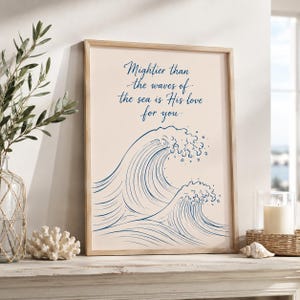 May include: A rectangular framed wall art print featuring a light beige background with a blue line drawing of two ocean waves. The text "Mightier than the waves of the sea is His love for you" is printed in blue cursive script above the waves.